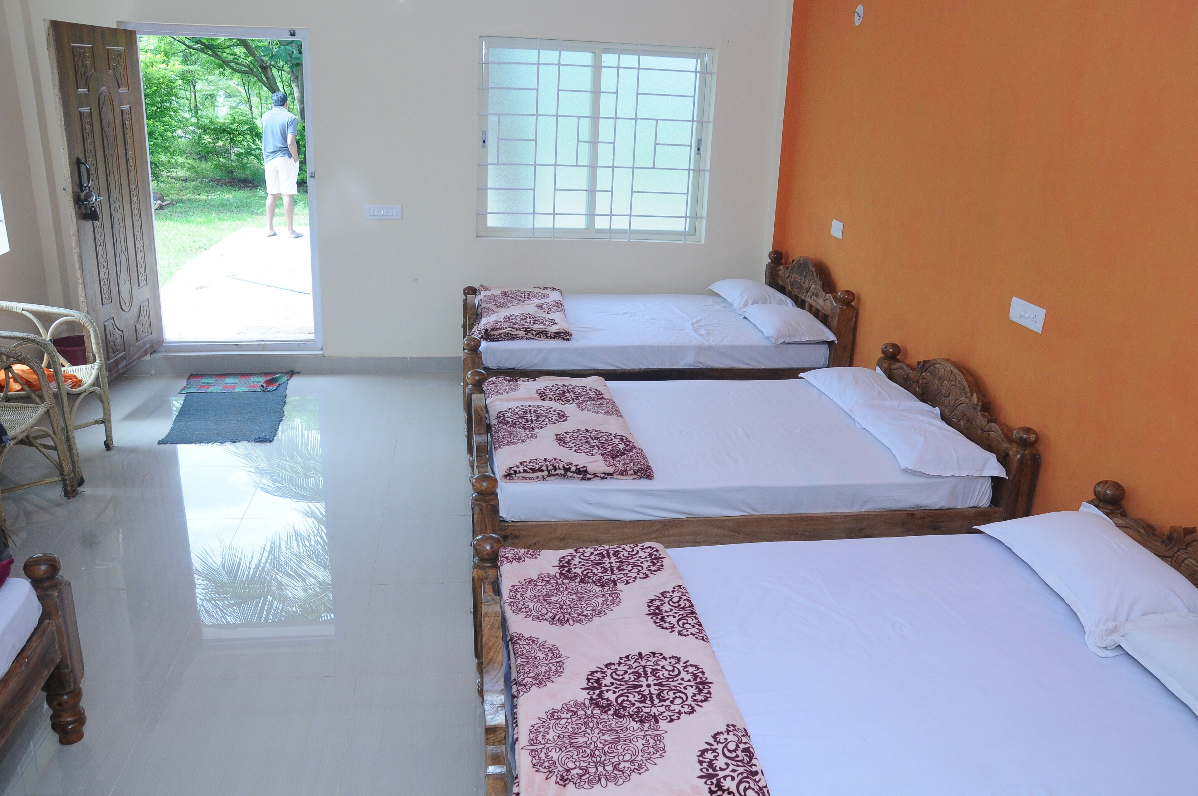 A hotel room with three wooden beds, a large window, and a view of the outdoors.