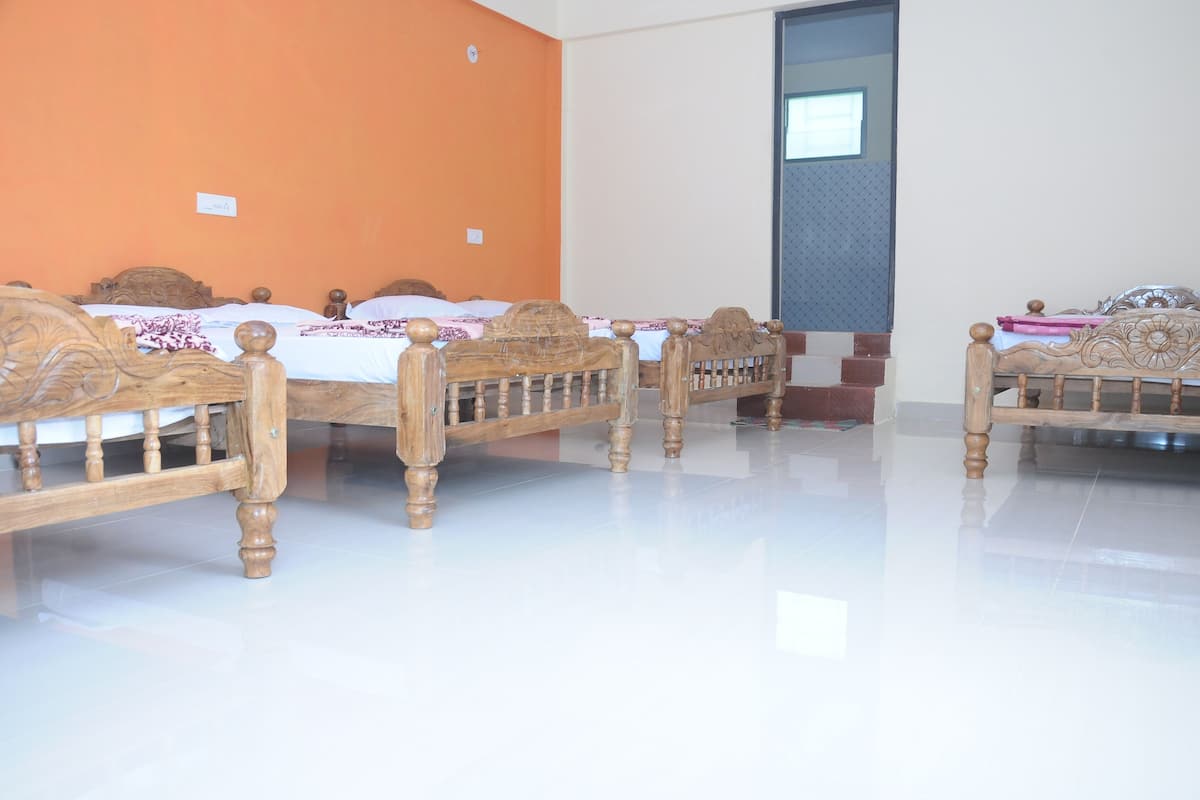 A hotel room with four wooden beds, a tiled floor, and an orange accent wall.