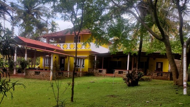 Un bâtiment jaune avec un toit rouge, entouré d’une pelouse et de palmiers.