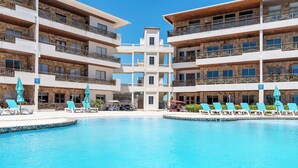 Ein Hotel mit zentralem Pool, mehreren Balkonen und Liegestühlen.