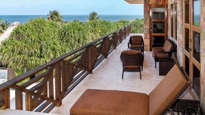 A balcony with wicker furniture, a view of the ocean, and a stone wall.