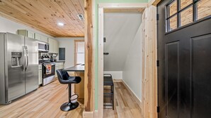 Una cocina moderna con electrodomésticos de acero inoxidable, techo de madera y puerta negra.