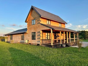Una baita in legno a due piani con un portico e una veranda coperta.