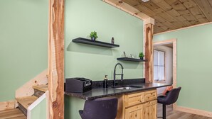 Una cocina con escalera de madera, encimera negra y armarios de madera.