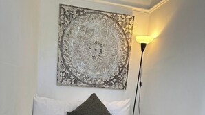 Uma cama com um cobertor verde, almofadas brancas e um ornamento decorativo na parede acima.