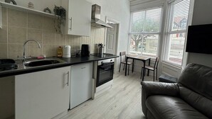Uma cozinha compacta com forno embutido, pia e área de refeições com mesa e cadeiras.