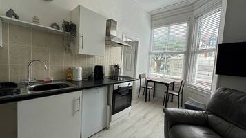 A compact kitchen with a built-in oven, a sink, and a dining area with a table and chairs.