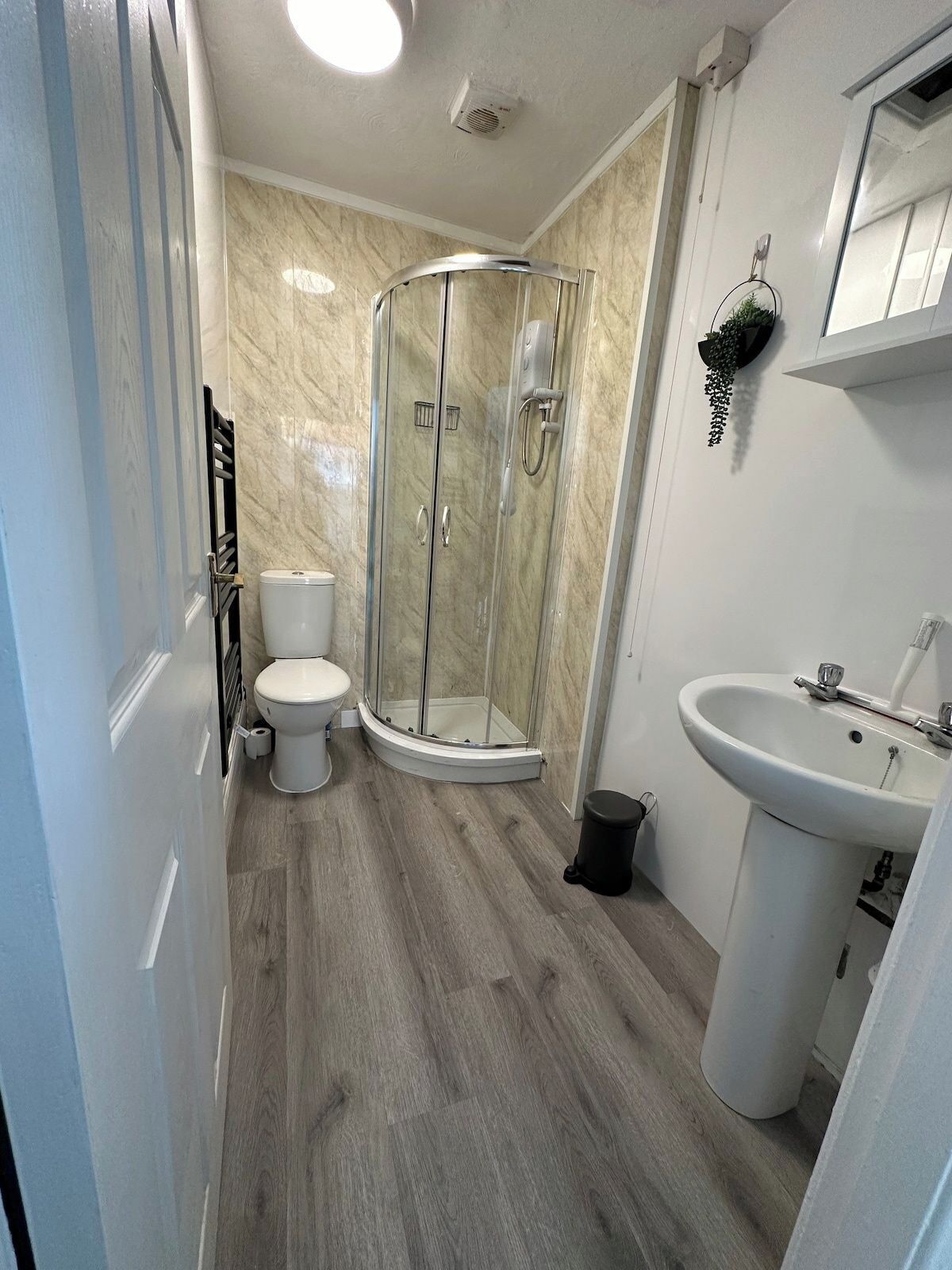 A bathroom with a glass-enclosed shower, a toilet, and a sink.