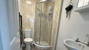 Uma casa de banho com cabine de duche em vidro, sanita e lavatório.