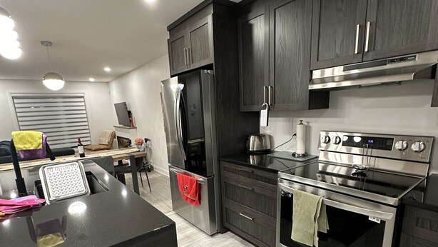 A modern kitchen with dark cabinetry, stainless steel appliances, and a central island. - Beautiful House in mont tremblant,ski hills,

You will feel like you’re at home. (Mont-Tremblant)