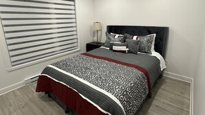 A modern bedroom with a large bed, a nightstand, and a window with blinds. - Beautiful House in mont tremblant,ski hills,

You will feel like you’re at home. (Mont-Tremblant)