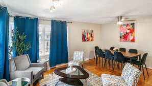 Una sala de estar moderna con una mesa de centro redonda, sofás grises y una zona de comedor con una mesa y sillas de madera.