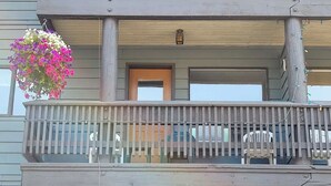 A multi-story building with a balcony featuring a wooden railing and a hanging flower basket. - Griz Inn Condo on the Hill - 100 steps from lift (Fernie)