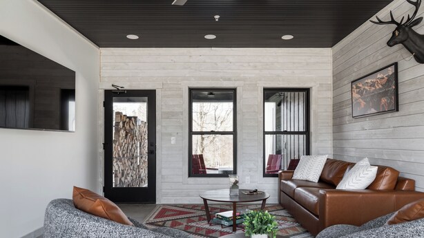 A modern living room with a fireplace, leather sofa, and a mounted deer head. - Spillway Lodges (Bellaire)