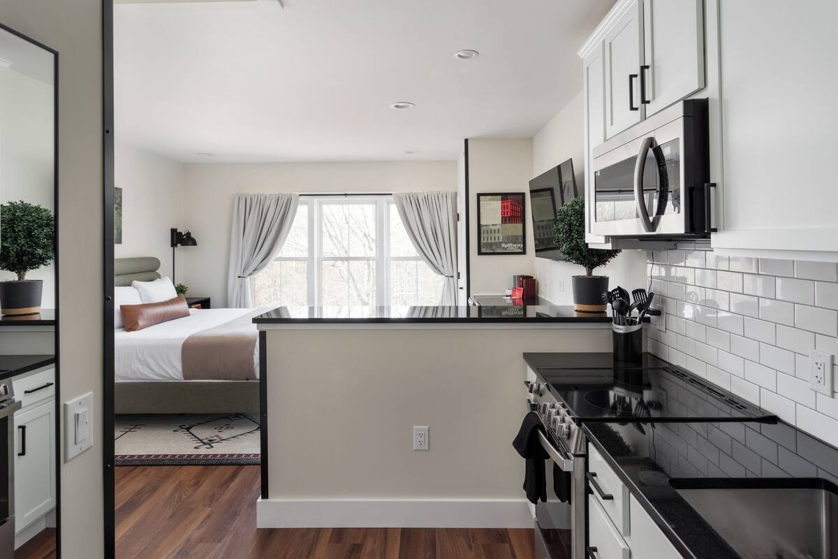 A modern kitchen with white cabinets, a black countertop, and stainless steel appliances.