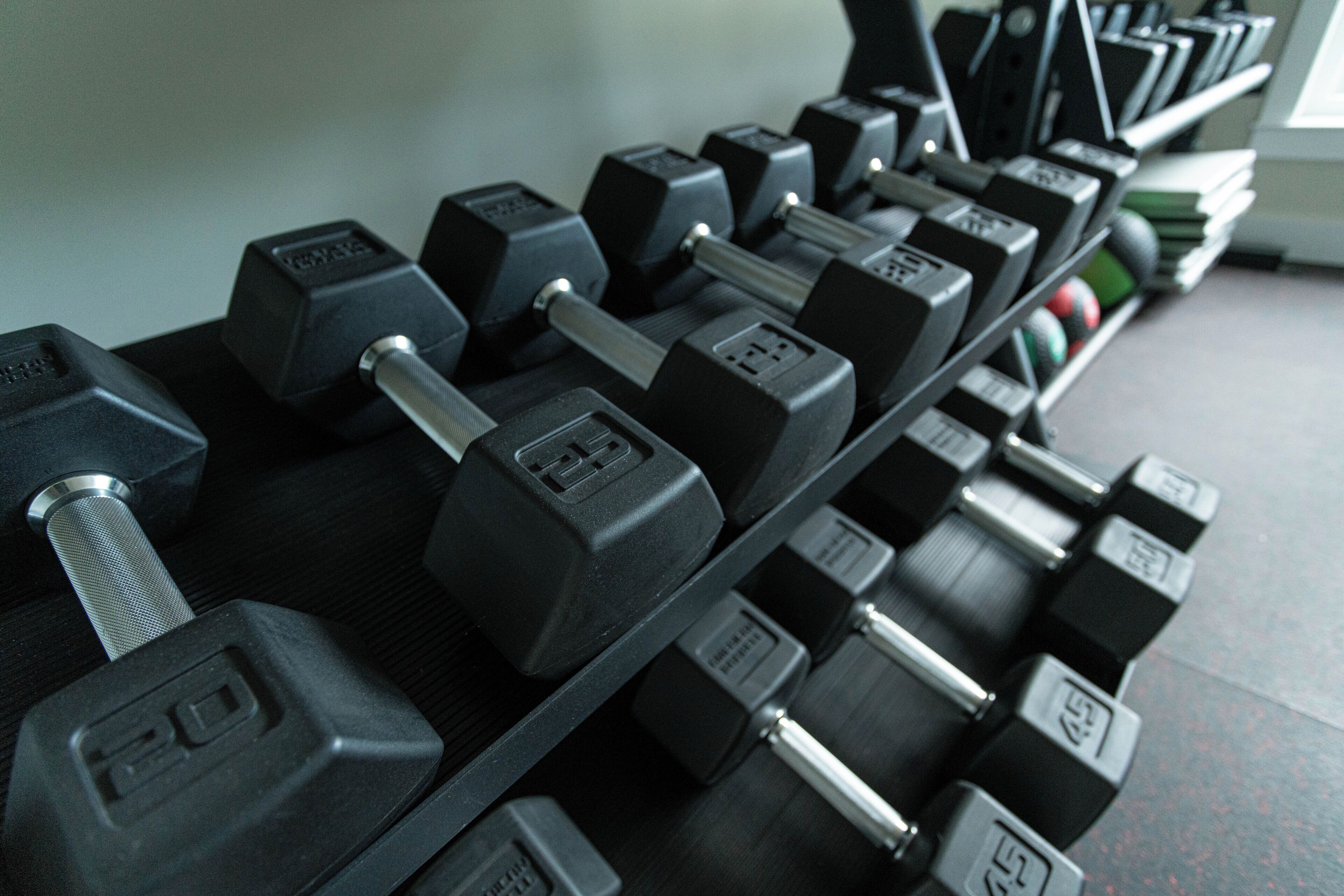 A rack of black dumbbells with weight markings, arranged on a shelf.