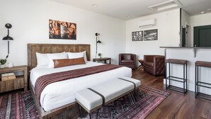 A modern hotel room with a large bed, a bench, a desk, a chair, and a TV. - Spillway Lodges (Bellaire)