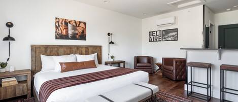 Una habitación de hotel moderna con una cama grande, un banco, un escritorio, una silla y un televisor.