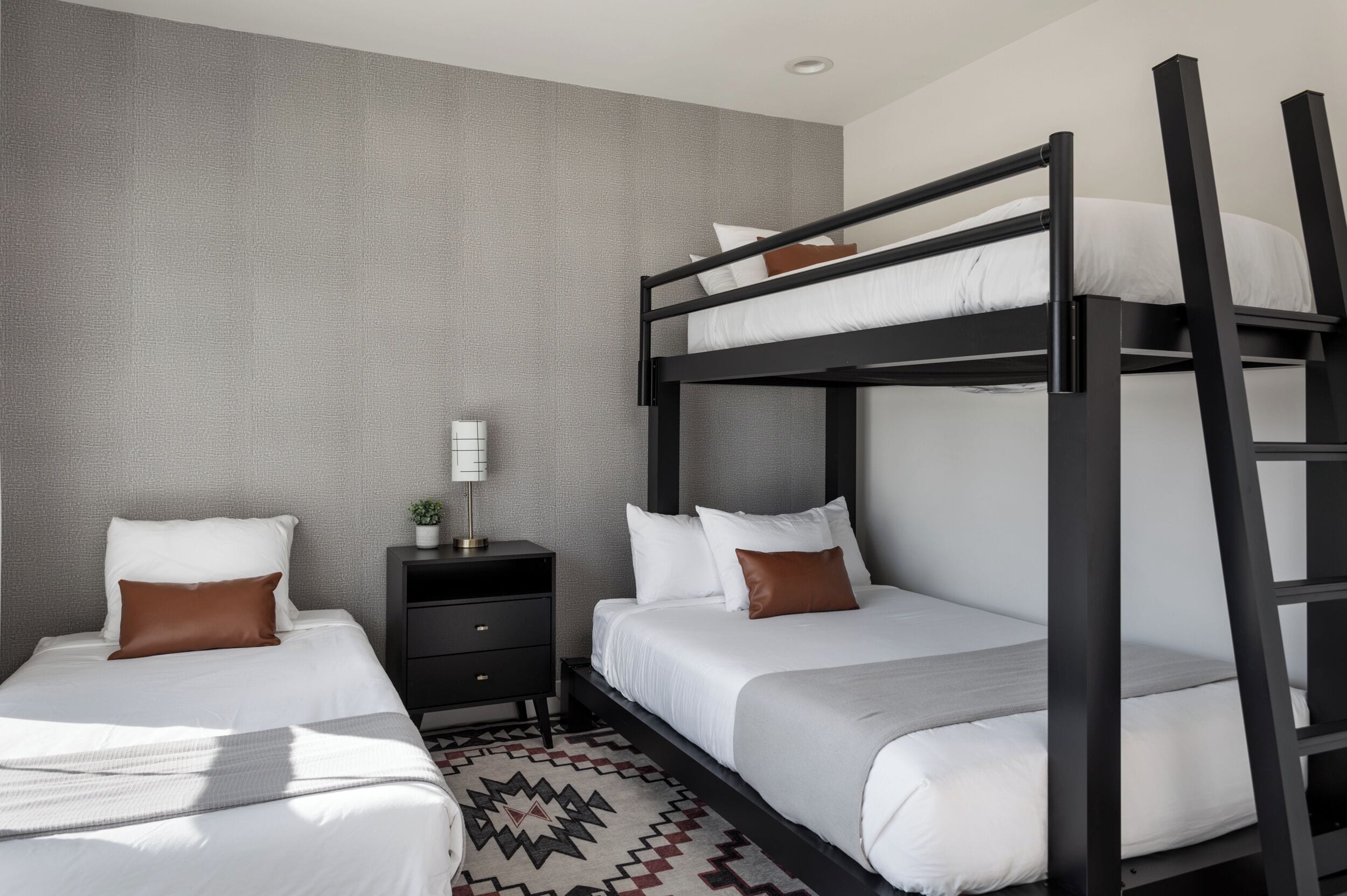 Una habitación de hotel con dos camas, una mesita de noche y una alfombra estampada.