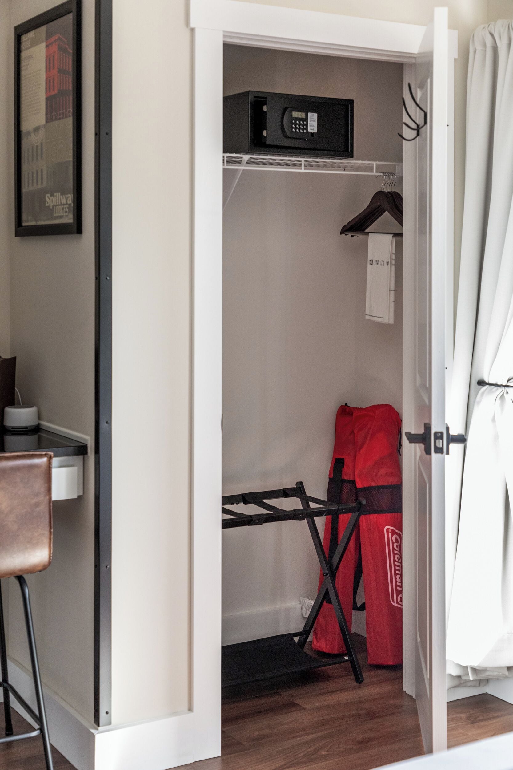 Una habitación compacta con un armario blanco, un microondas, una bolsa para ropa roja y un perchero.