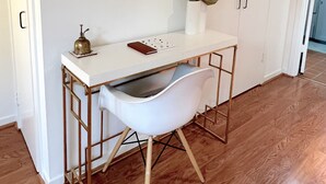 A white desk with a round mirror, a vase, and a book on it.