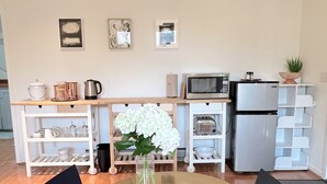 A small kitchen with a round table, two chairs, a refrigerator, a microwave, and a sink.