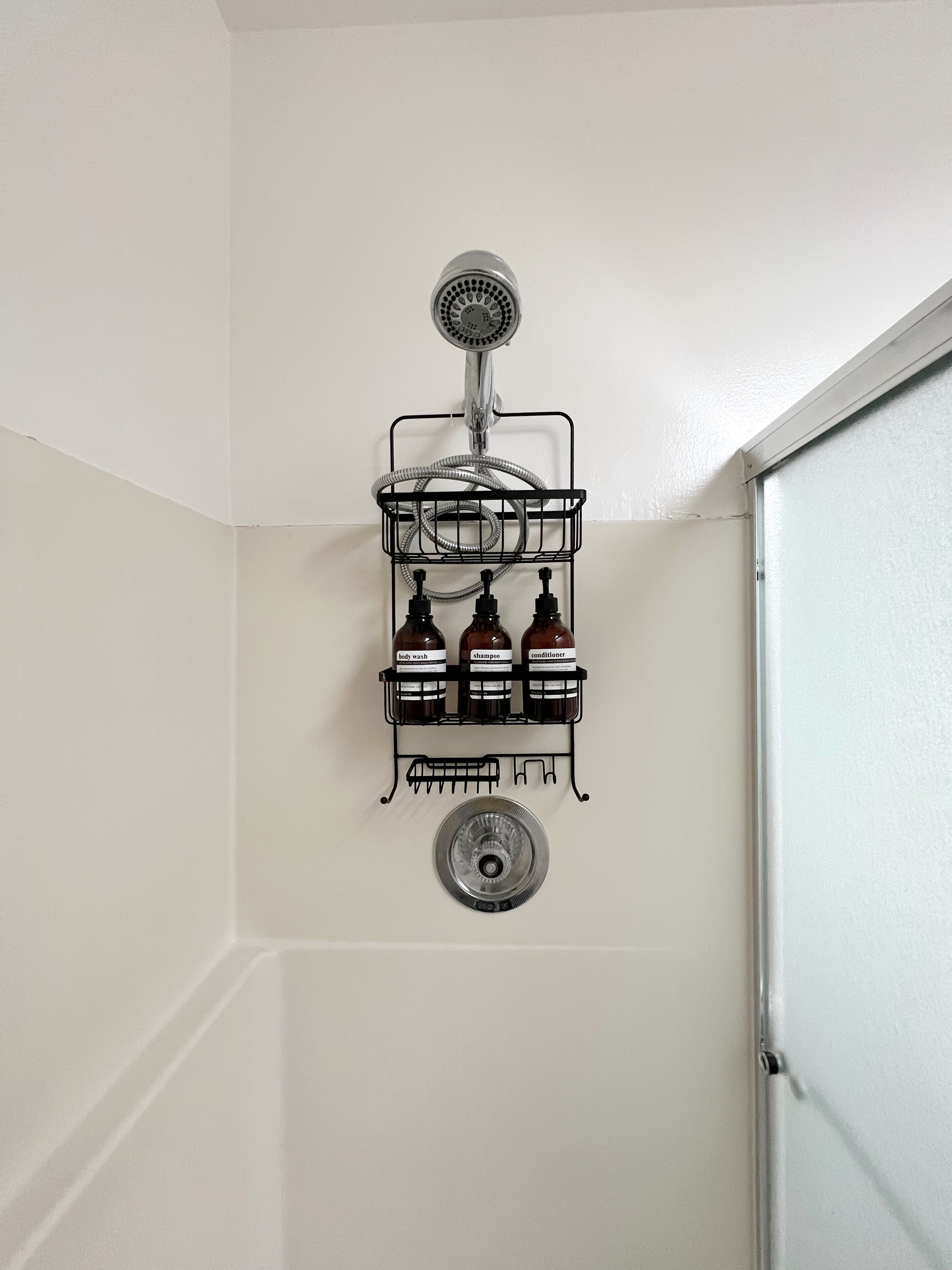 Une salle de bain avec une douche, un porte-savon noir et un lavabo en verre.