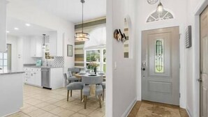 Una cocina moderna con comedor, un pasillo con una puerta y piso de baldosas.