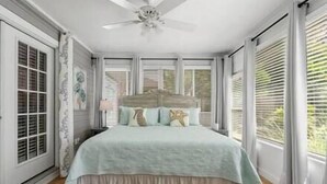 Un dormitorio con una cama grande, ventilador de techo y vistas a zonas verdes.