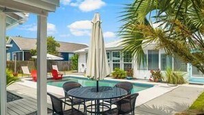 Un patio trasero con piscina, un área de patio techada y mobiliario exterior.