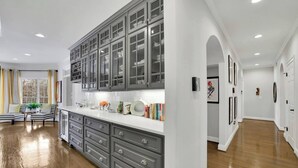A modern kitchen with grey cabinets, a white countertop, and a dining area with striped chairs. - Serene Farms Hot Tub Pool Sunroom on 7 Acres (Hiram)