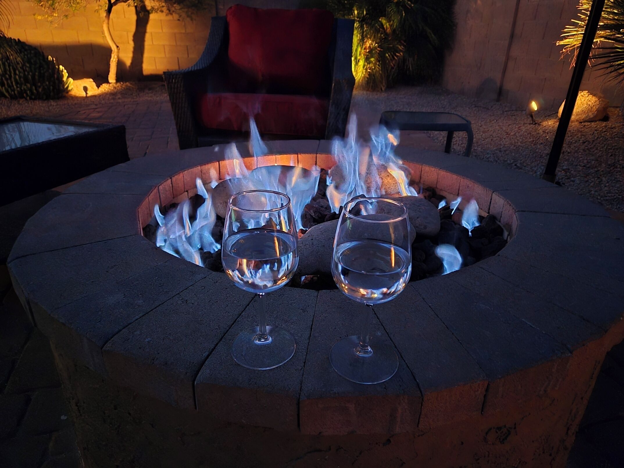 A circular fire pit with two glasses of water placed on it.