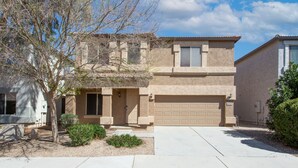 A two-story building with a beige facade, a garage, and a small front yard with landscaping. - Newly Remodeled Beautiful Home and Large Sparkling Pool, New Hot Tub & Game Room (San Tan Valley)
