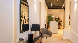 A modern interior with a sofa, a lamp, a mirror, and a dining area in the background.