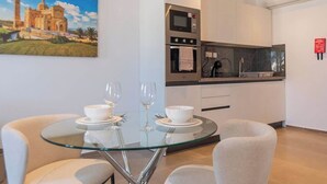A modern kitchen with a microwave, oven, and sink. There is a glass table with two bowls and wine glasses.