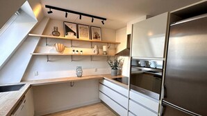 A modern kitchen with a built-in oven, stainless steel appliances, and wooden countertops. - Løvstræde baghus 4 th top floor (København)