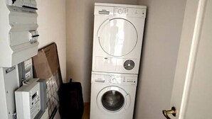 A laundry room with stacked appliances, including a dryer and a washing machine. - Løvstræde baghus 4 th top floor (København)