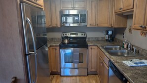 A kitchen with stainless steel appliances, wooden cabinets, granite countertops, and a wooden floor. - La Plata Views | In-Town | Pool | Hot Tub (Durango)