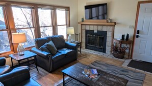 A living room with a fireplace, a sofa, a coffee table, and a TV mounted above the fireplace. - La Plata Views | In-Town | Pool | Hot Tub (Durango)