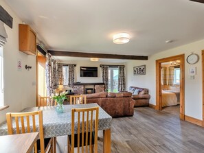 A cozy living room with a fireplace, a dining area with a table and chairs, and a sofa.
