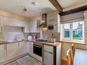 A modern kitchen with white cabinets, a built-in microwave, a gas stove, and a refrigerator. - Milking Parlour - UK48911 (Allonby)