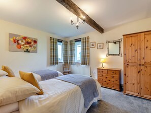 Une chambre avec deux lits, une commode, un miroir et un radiateur.