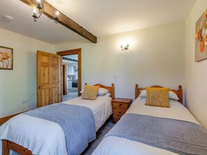 A bedroom with two beds, wooden headboards, a wooden door, and a light fixture on the wall. - Milking Parlour - UK48911 (Allonby)