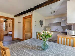 Una cocina moderna con armarios blancos, una mesa de madera y un jarrón con flores.
