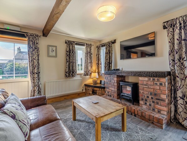 A cozy living room with a fireplace, leather sofa, and a wooden coffee table.