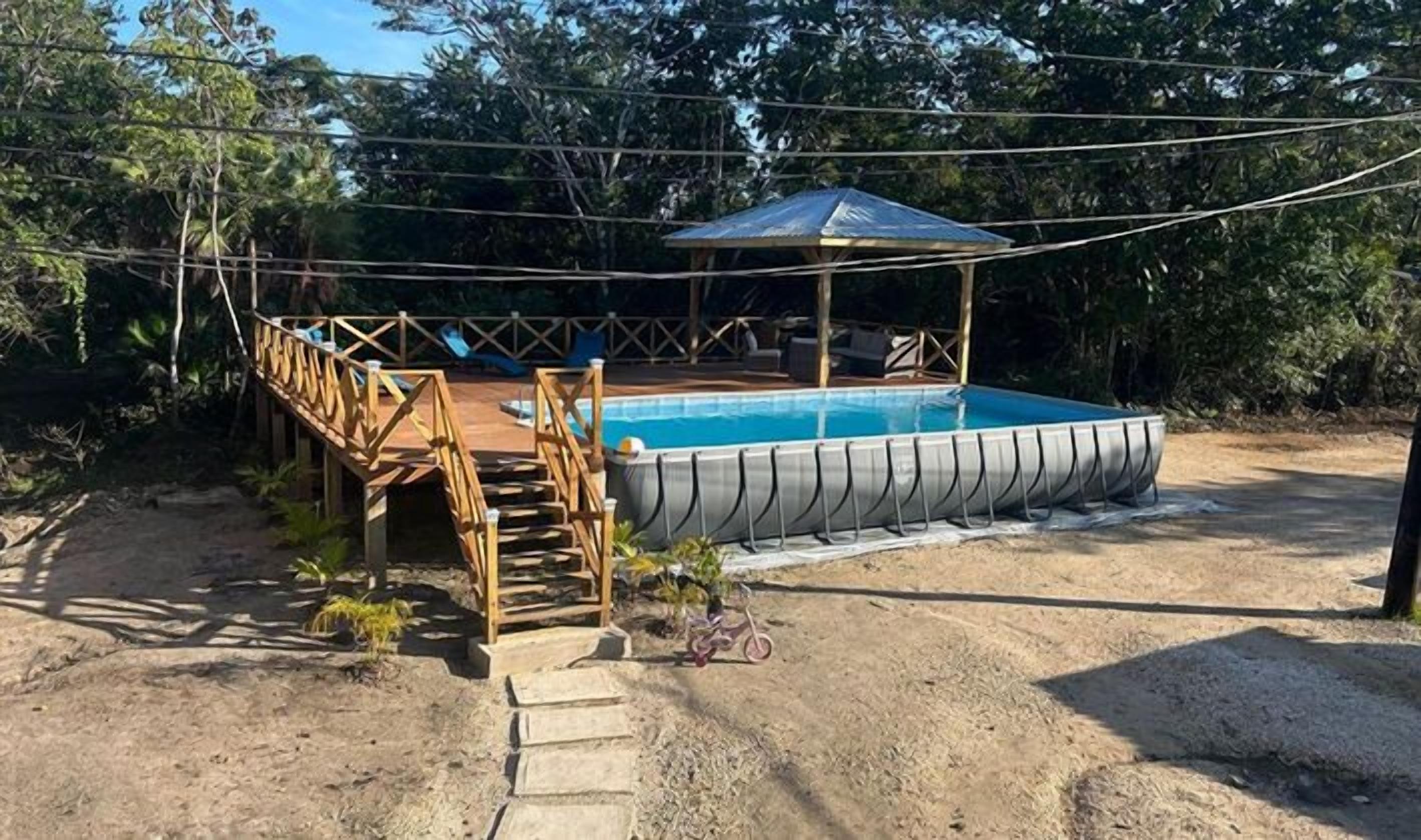 Piscina com deck de madeira e área de estar coberta.