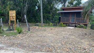 A rustic wooden structure with a gravel path leading to it, surrounded by dense greenery.