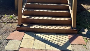A wooden staircase leading to a house with a red exterior and a white door. - Refuge by Southern Oaks. Charming 3 bed 2 bath. Very close to Lake Murray! (Gilbert)