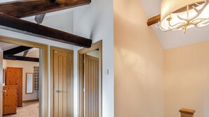 Ein Flur mit Holztüren, einer Holztreppe mit Handlauf und einer Deckenleuchte.