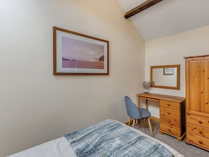 Un dormitorio con cama, escritorio, silla, armario y un cuadro en la pared.
